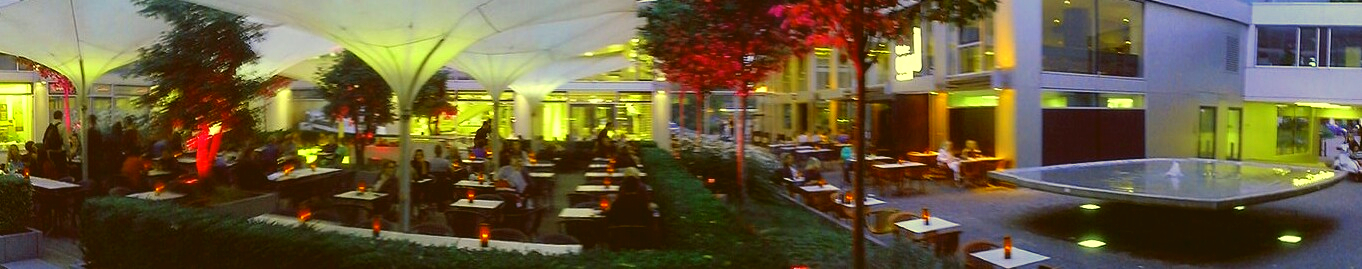 Cafe  mit riesigen leuchtenden Blumentrögen München